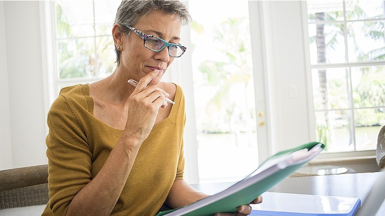 Woman smiles while looking down at folder in their home