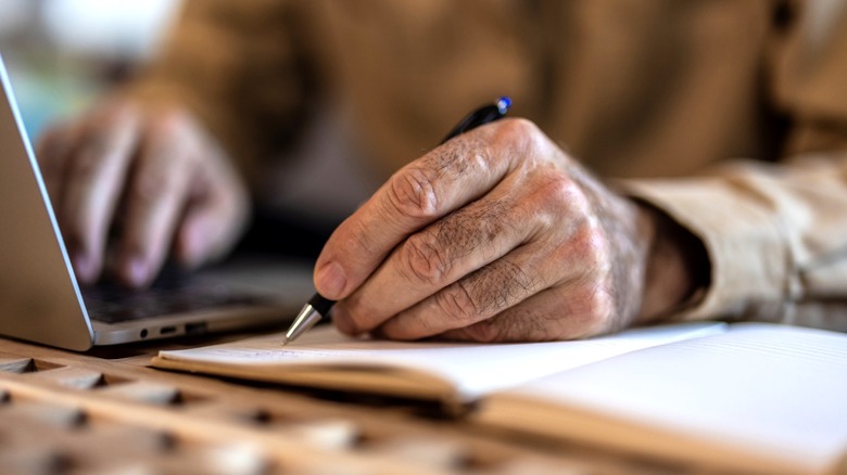 Older person writing in notebook