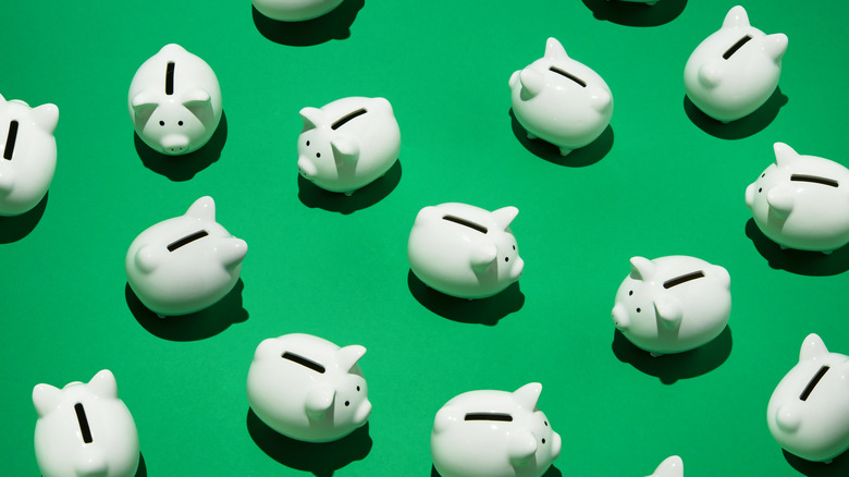 white piggy banks scattered on green background