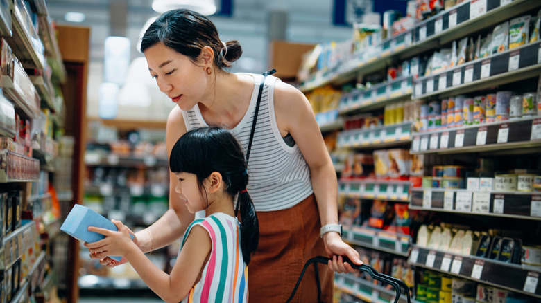 A mother and daughter examining an item from a store shelf.