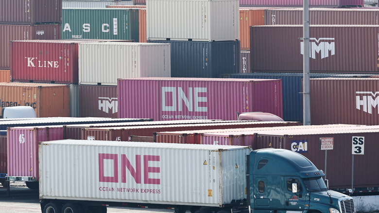 A truck drays away a shipping container from a congested port.