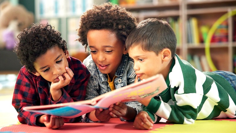 Three little boys reading a book together