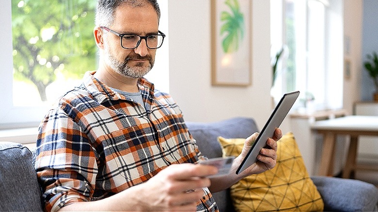 Man examines card and tablet