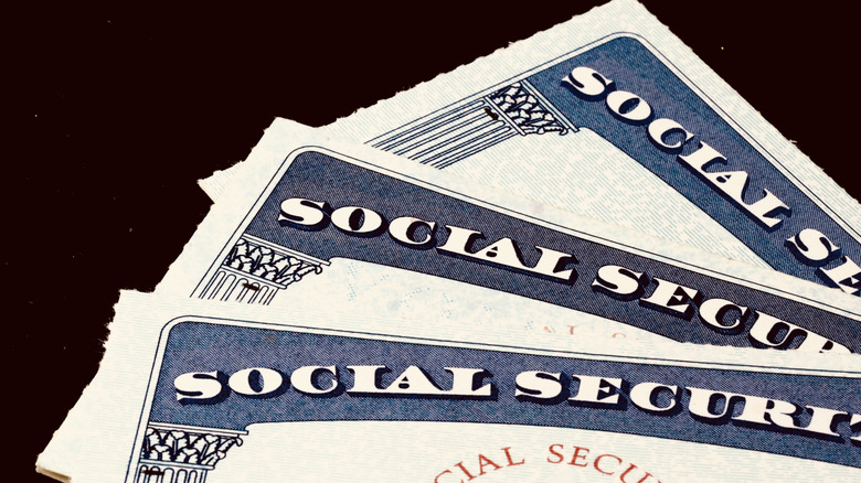 Three Social Security cards laying spread out, one on top of another.