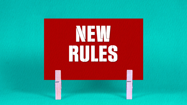 A red sign reading 'New Rules' in front of a green background.