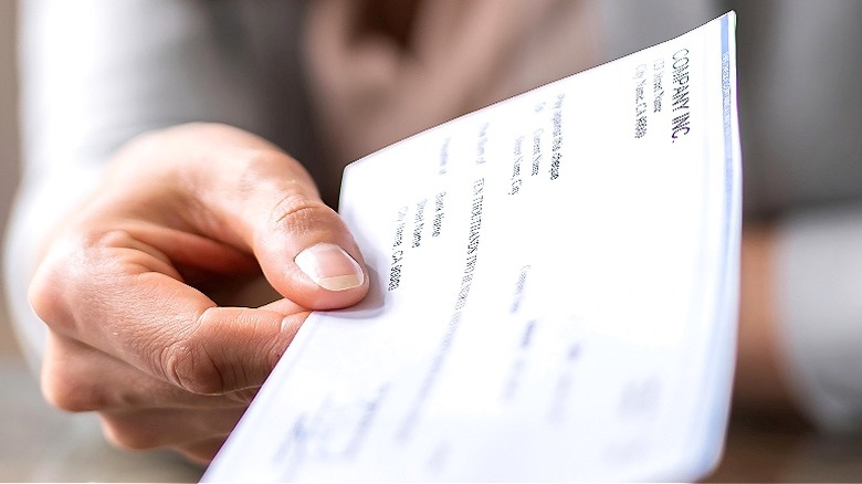 Person holding, extending paycheck forward