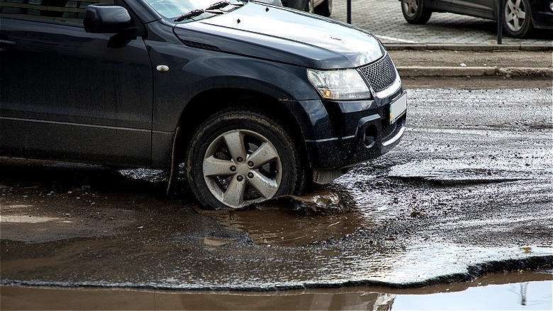 Car driving through large pothole