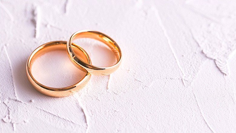 Two gold colored wedding bands sitting on a white surface