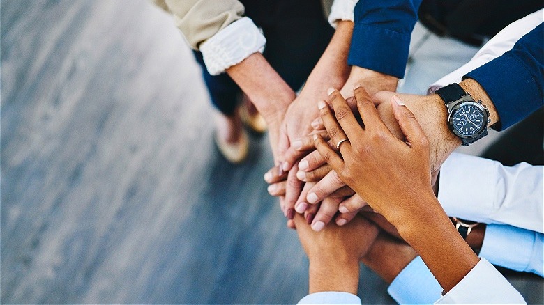 Workers stacking hands in unity