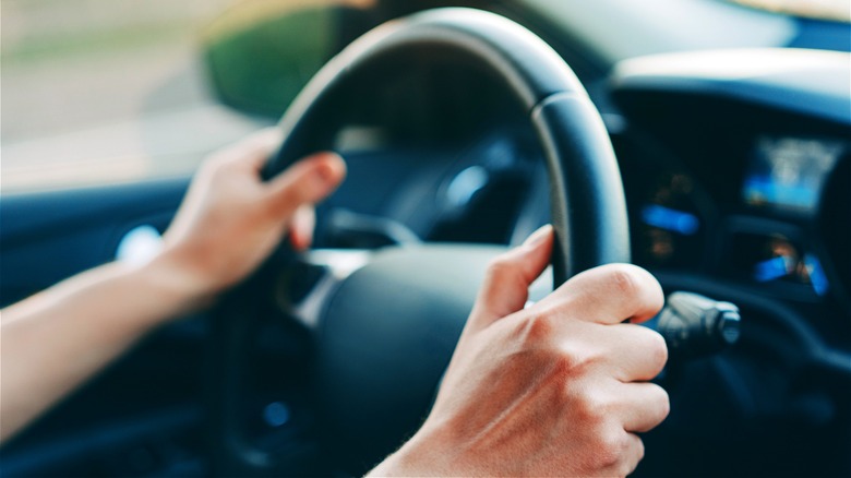 Hands on car steering wheel