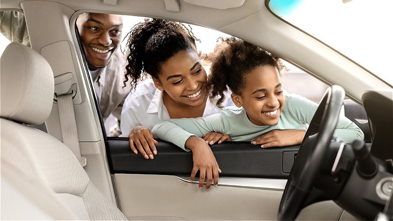 Family examining a new car