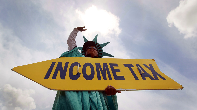 A person holding income tax sign while wearing Statue of Liberty costume