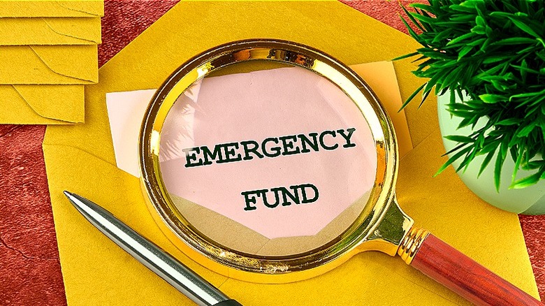 Magnifying glass over 'EMERGENCY FUND' paper inside golden envelope