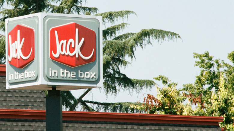 A pole mounted Jack in the Box sign in front of a restaurant