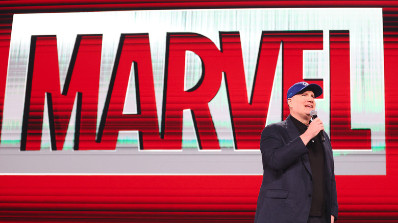 Kenin Feige standing in front of a blown up Marvel logo