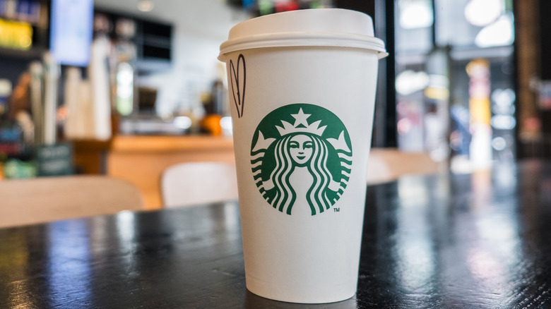 A close-up of a Starbucks coffee cup on a table in a cafe