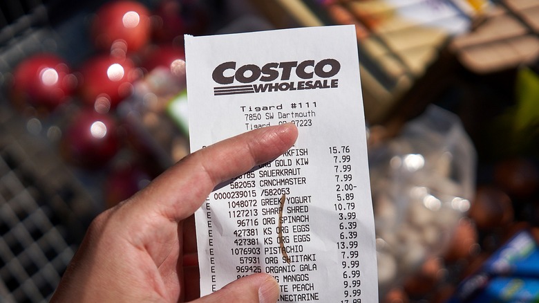 Hand holds Costco receipt with checkout mark