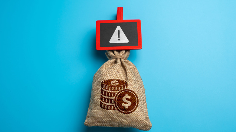 A warning symbol over a money bag