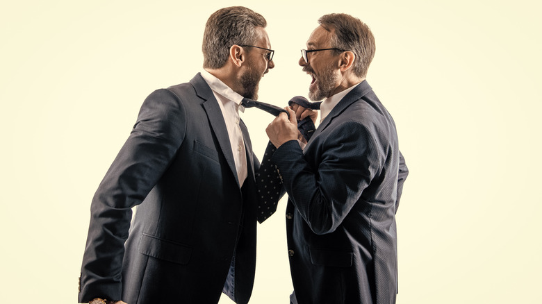 Men in suits yelling at each other and grabbing their ties