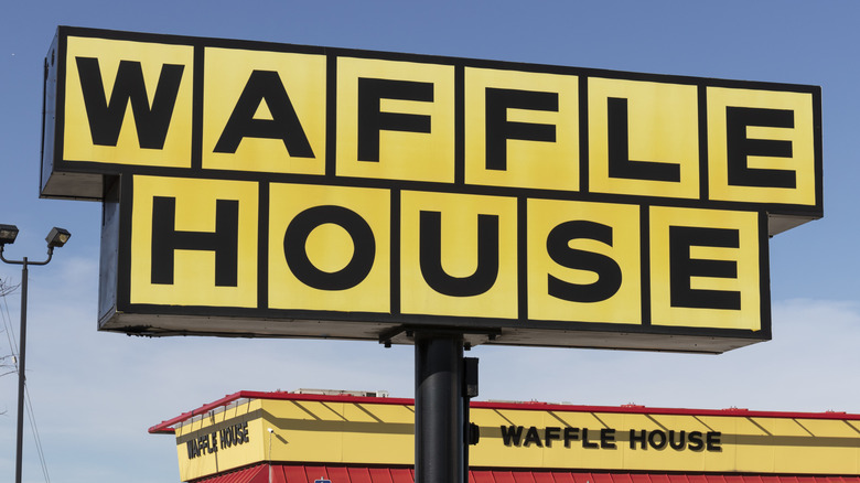 A bright yellow Waffle House sign and restaurant on a sunny blue day.