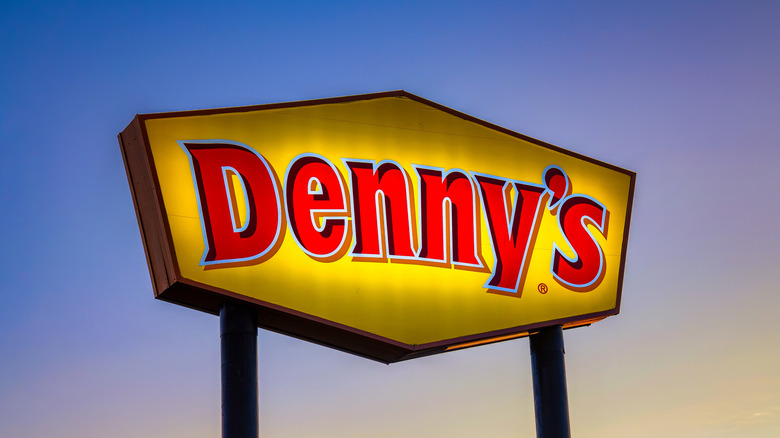 A lit-up Denny' sign against a twilight sky.