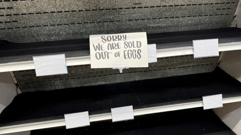 Empty shelves with a sign posted reading "Sorry, we are sold out of eggs."