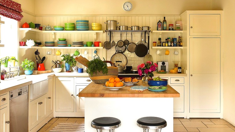 A kitchen with an island, open shelving, and a closed pantry