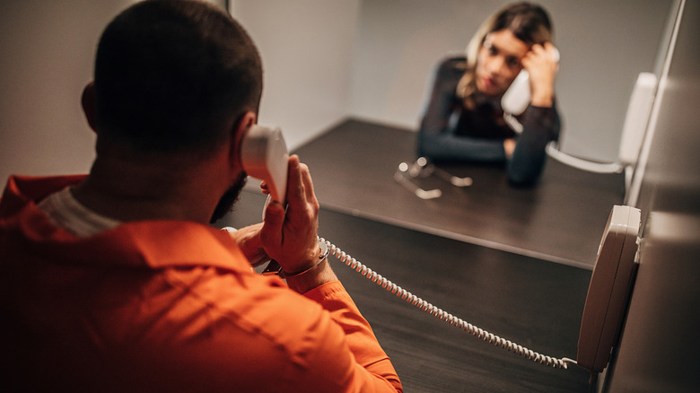 A prisoner talking to a person on the phone in the visiting room