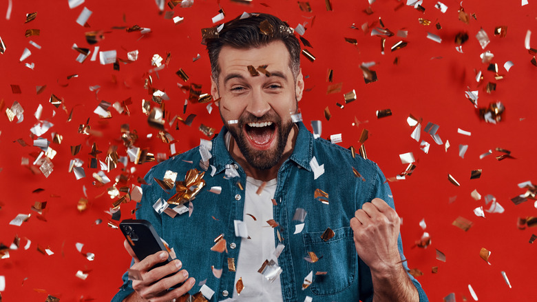 A man cheering while he is showered in confetti.