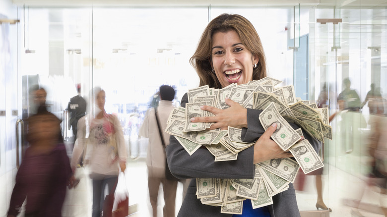 An excited woman holding a pile of money.