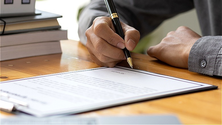 Person signing document with pen