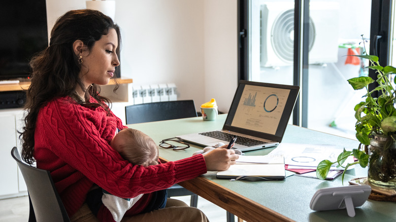 Woman working from home while breastfeeding infant