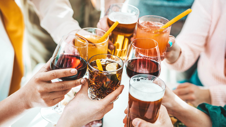 A group of friends "cheers" alcoholic drinks while out dining.