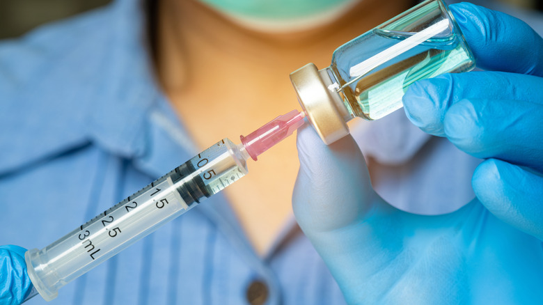 A medical syringe inserted into a vial of clear liquid.