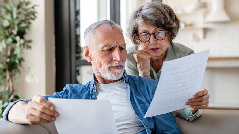 A mature man and woman scrutinizing paperwork