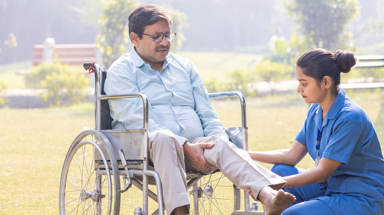 A man in a wheelchair lifting his leg with the assistance of a nurse