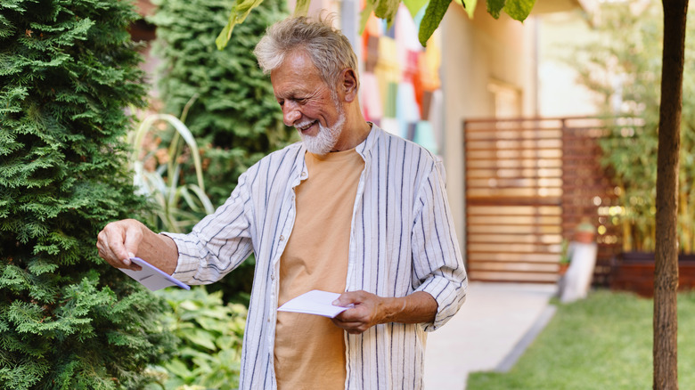 A senior man holding and envelope while reading a letter