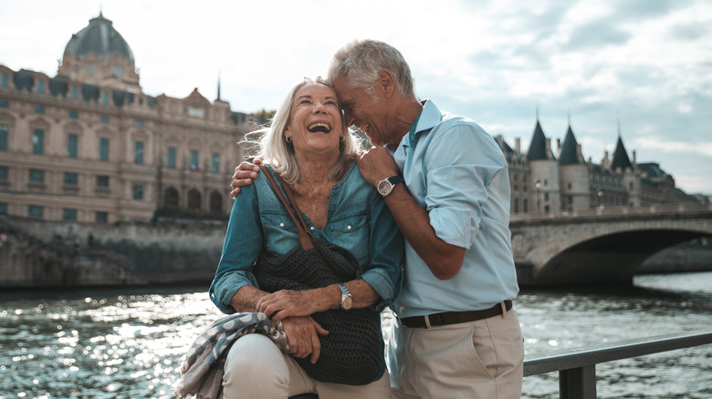 A mature couple laughing while embracing in front of the River Seine