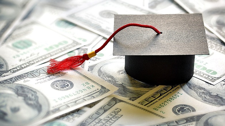 Mortarboard with red tassel rests on pile of money