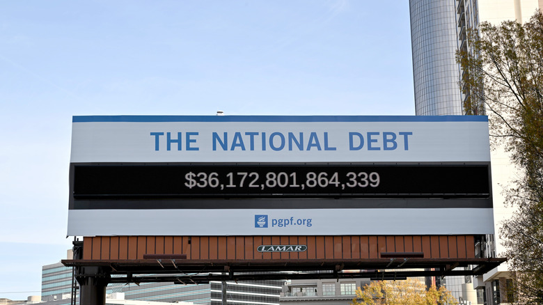 A billboard displaying the live national debt total, with total current as of December 2024.