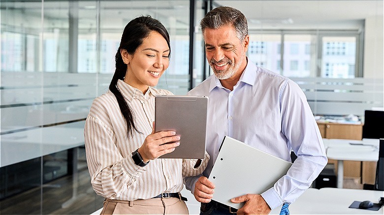 Colleagues smiling, looking at tablet