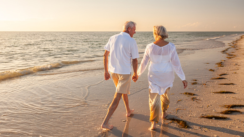 retired older couple walking on a beach