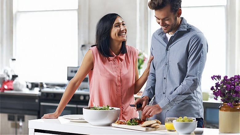 Couple smiling, cooking at home