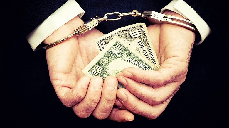 handcuffed and holding $10 bill