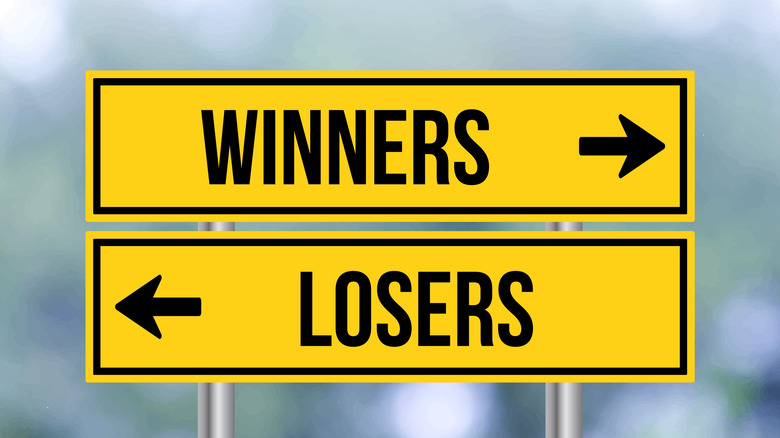 Yellow road signs reading winners and losers