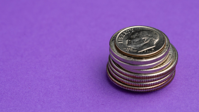 A stack of coins with a dime on top.