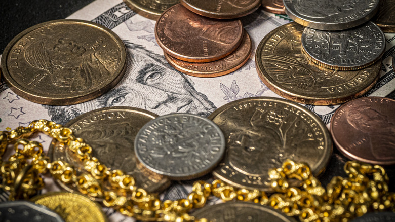 A gold ring on a pile of US dollar bills, coins