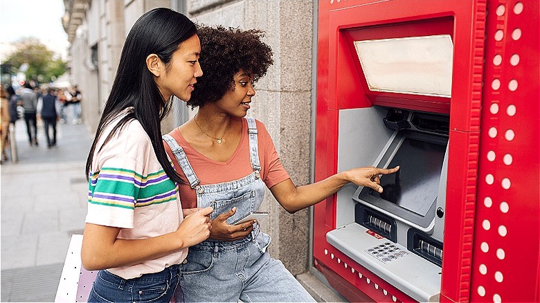 Two people using an ATM