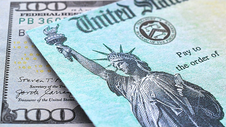 U.S. Treasury check lying atop a $100 bill