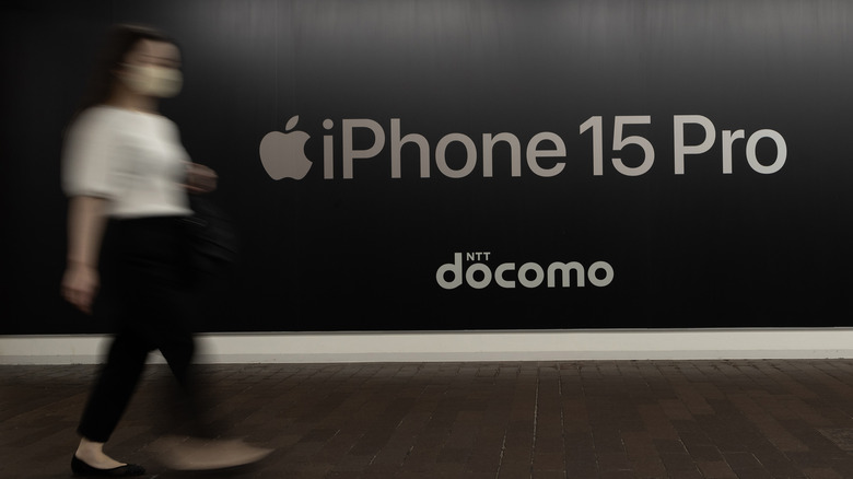 Woman walks past an iPhone 15 Pro ad